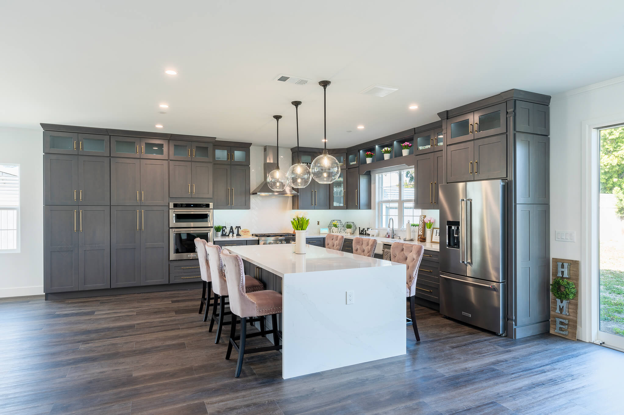 A modern kitchen includes stylish gray cabinets and intuitive light fixtures.